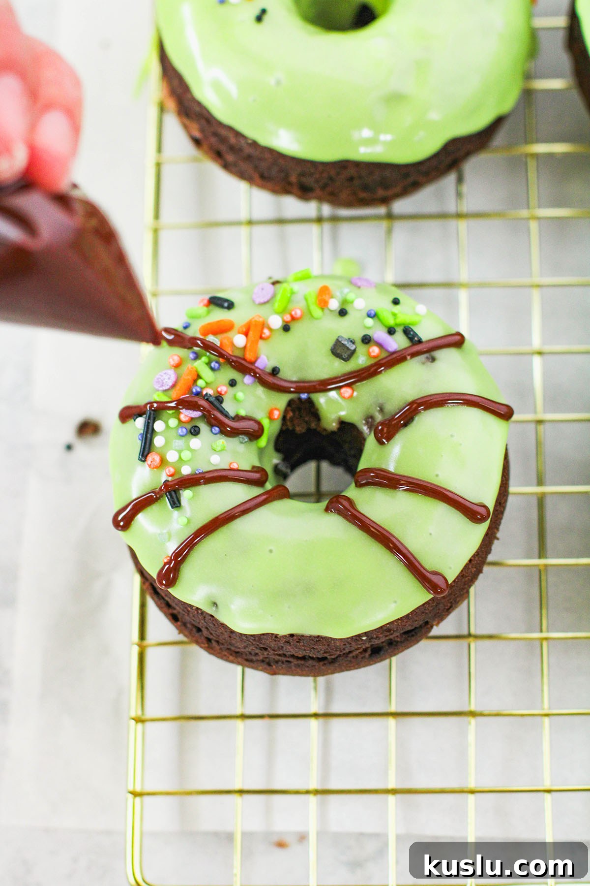 Spider Donuts Guide: How to Make Creepy Halloween Donuts 10 Piping chocolate glazed spider legs to a green glazed chocolate donut.