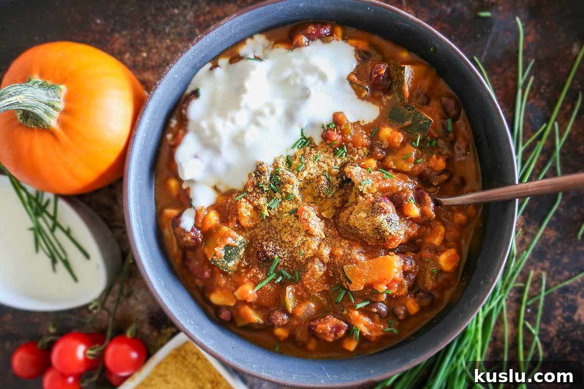 bowl of vegan pumpkin chili with a miniature pumpkin on the side