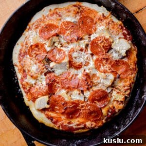 Sourdough Cast-Iron Pizza Without Yeast: Crispy Homemade Pie 14 Pepperoni tops the sourdough pizza in a cast iron skillet.