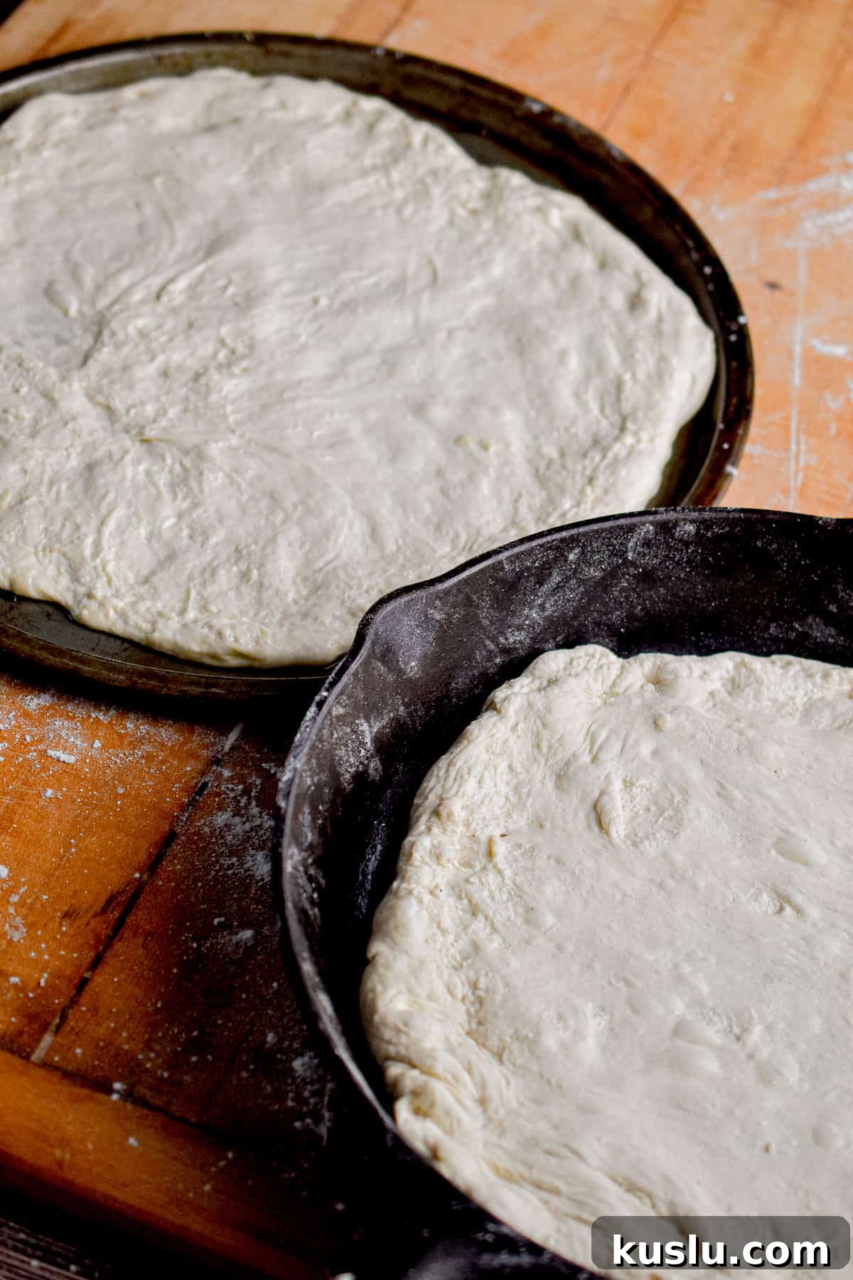 Sourdough Cast-Iron Pizza Without Yeast: Crispy Homemade Pie 8 The two doughs have been flattened and shaped. One is on a pizza pan and one is in a cast iron skillet.