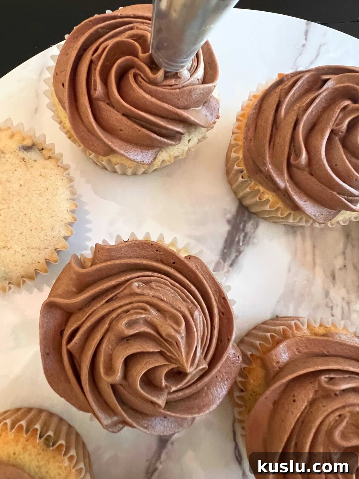 Decadent Chocolate Chip Cupcakes with Gooey Centers 5 Piping chocolate swirls onto cooled chocolate chip cupcakes.
