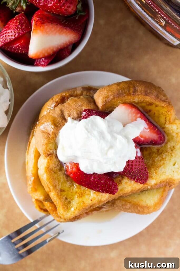 Classic French Toast Recipe: Crispy Edges and Creamy Center 4 Overhead shot of a stack of french toast with a bowl of strawberries and bottle of maple syrup.