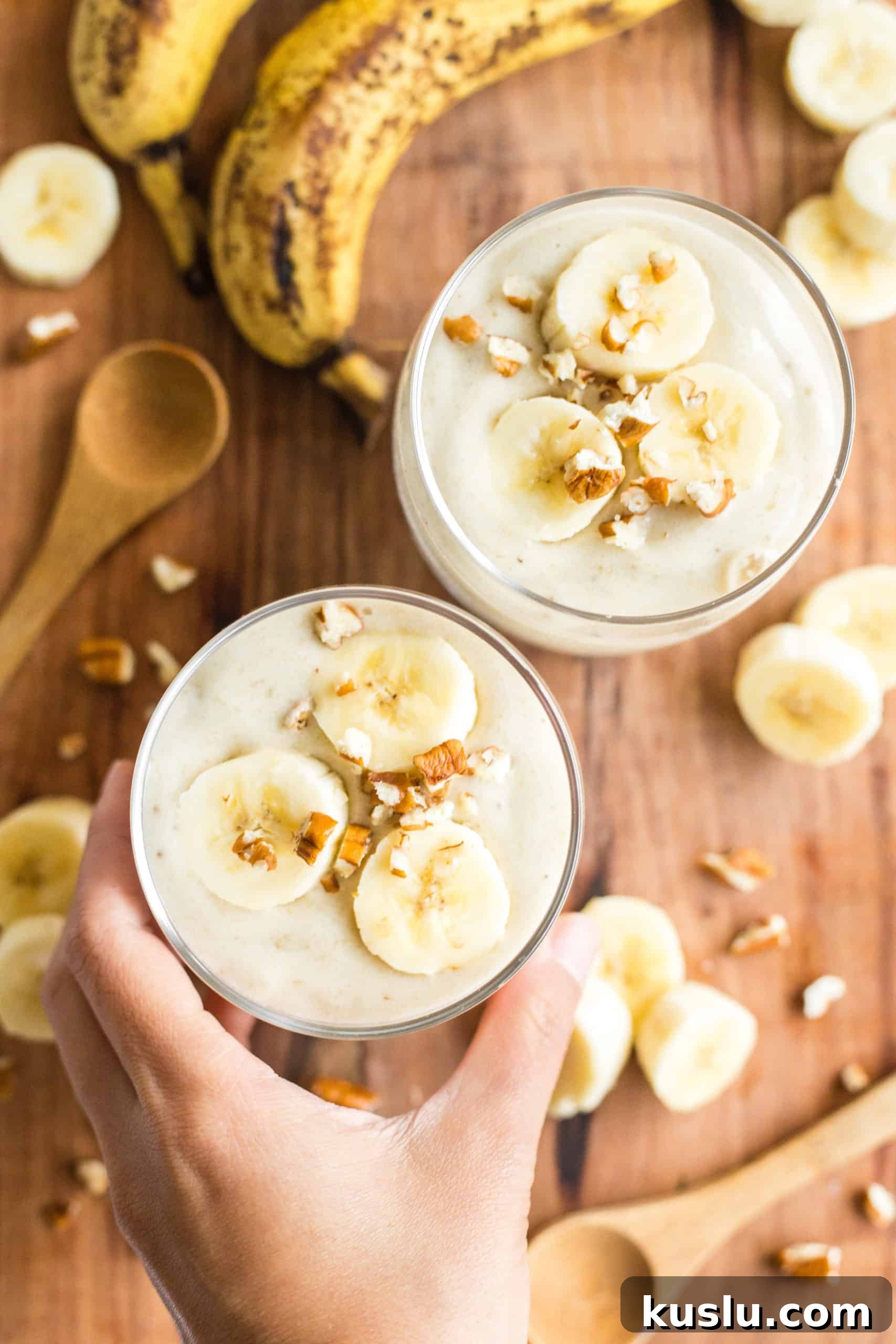 Homemade banana ice cream served in two glasses on a wooden board