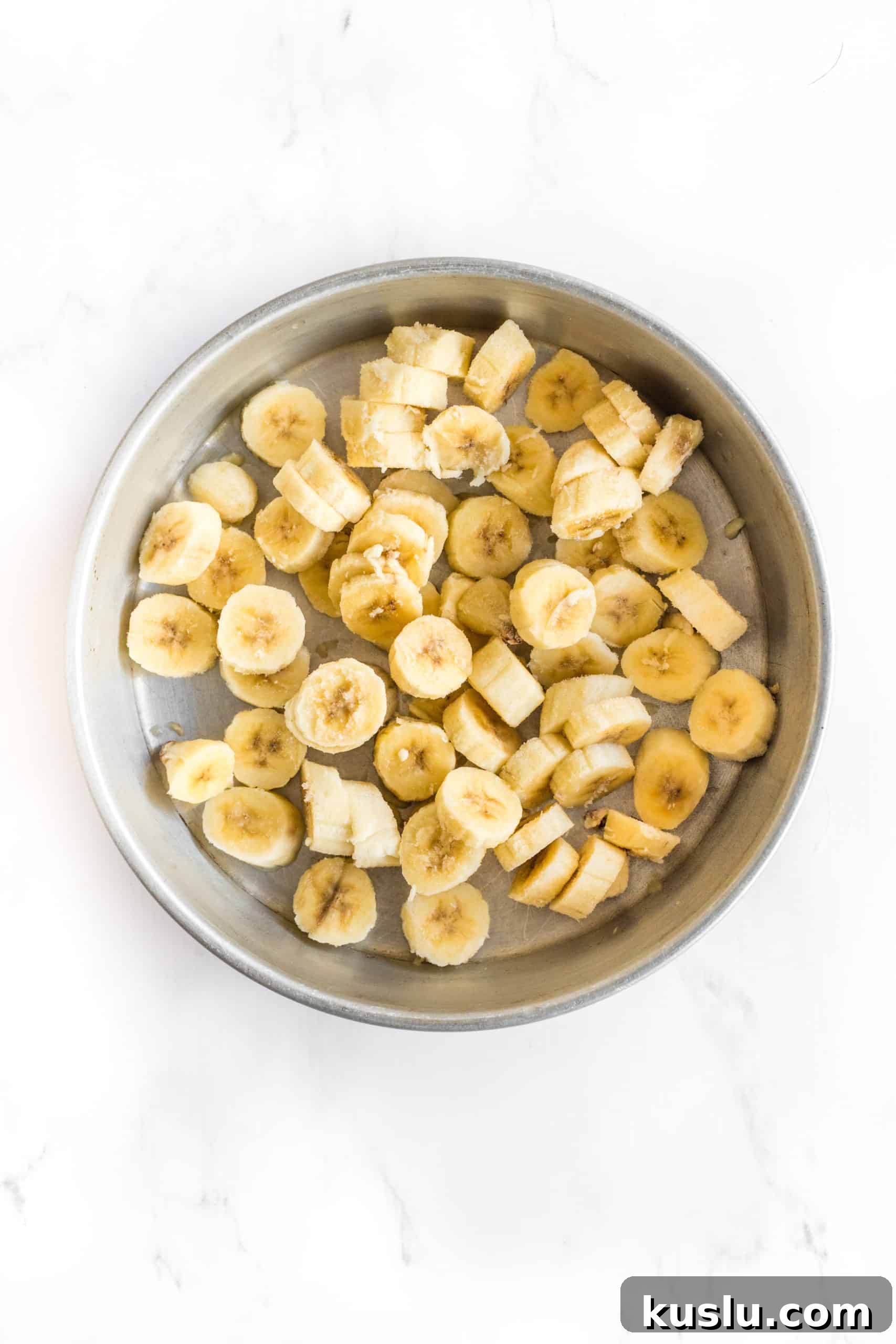 Sliced frozen bananas in a large metal bowl.