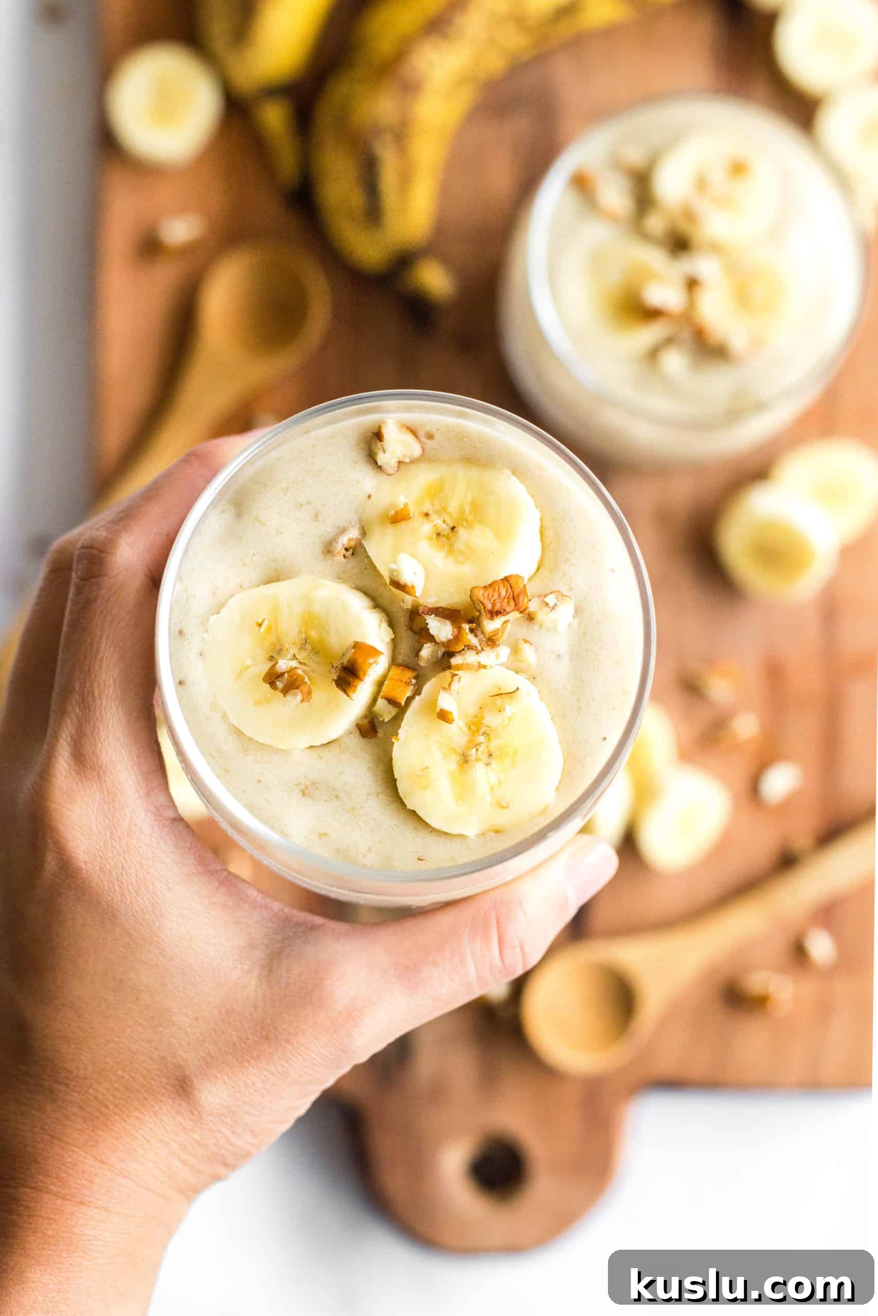 Hand holding up a glass of dairy-free banana ice cream 