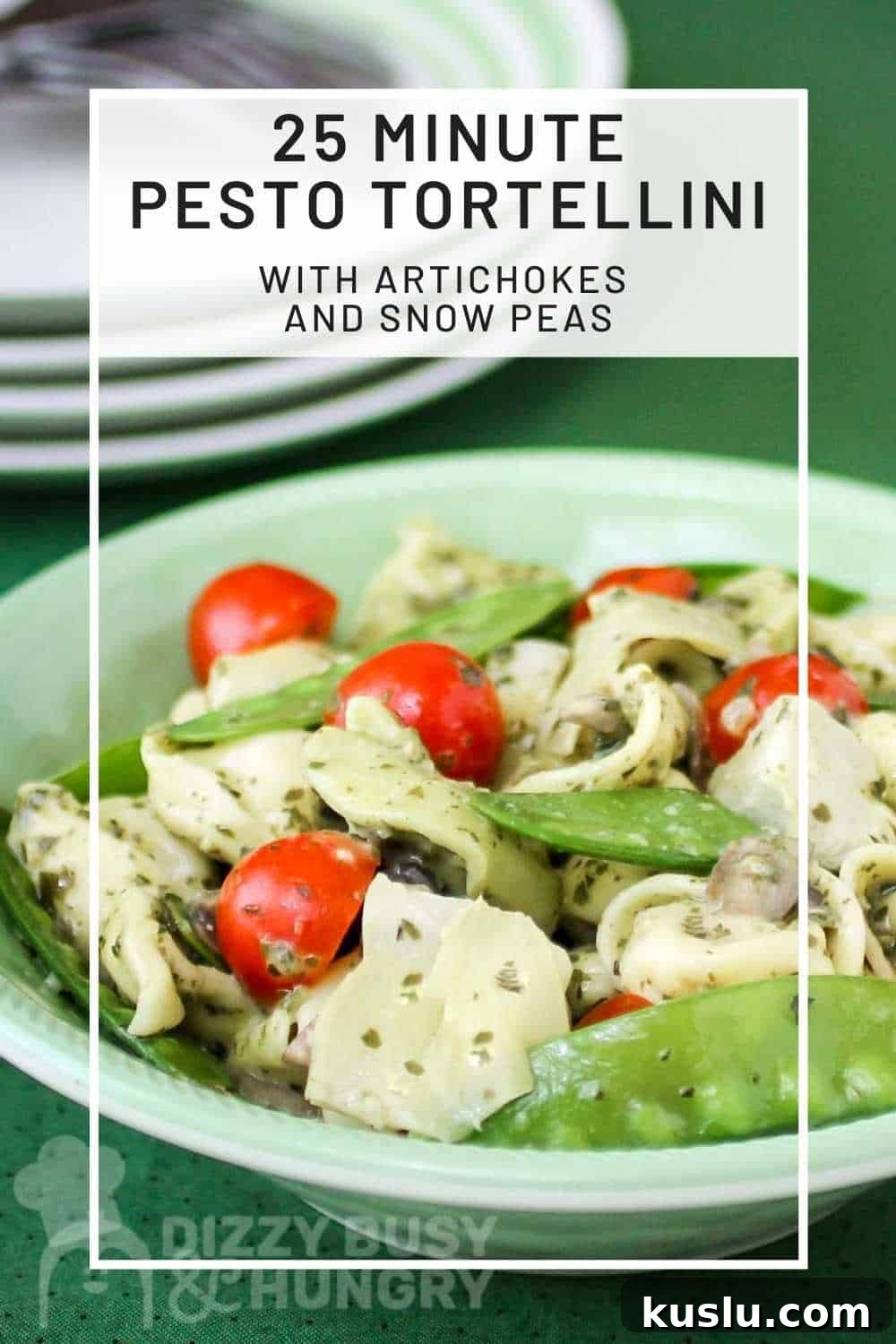 Pesto Tortellini with Artichokes and Snow Peas Recipe 2 Close up shot of pesto tortellini in a green bowl with plates and silverware in the background.