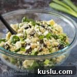 Pesto Tortellini with Artichokes and Snow Peas Recipe 6 Side shot of quinoa salad in a glass bowl with a black spoon on a blue surface with scallions in the background.