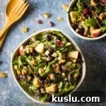 Pesto Tortellini with Artichokes and Snow Peas Recipe 7 Overhead view of two apple walnut salad bowls on a black surface.