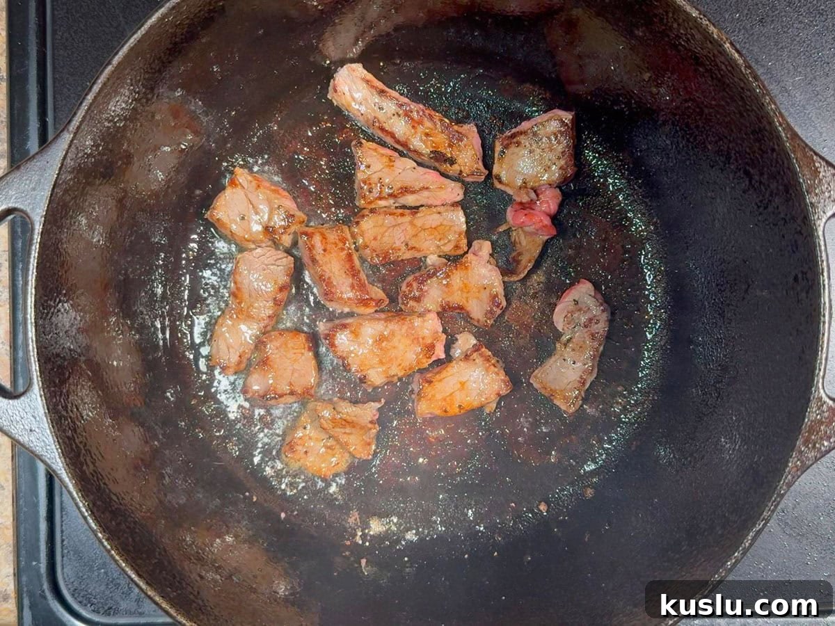 Southern Grillades and Grits Recipe: Classic New Orleans Comfort Food 5 Pieces of browned round steak cooking in a cast iron Dutch oven.