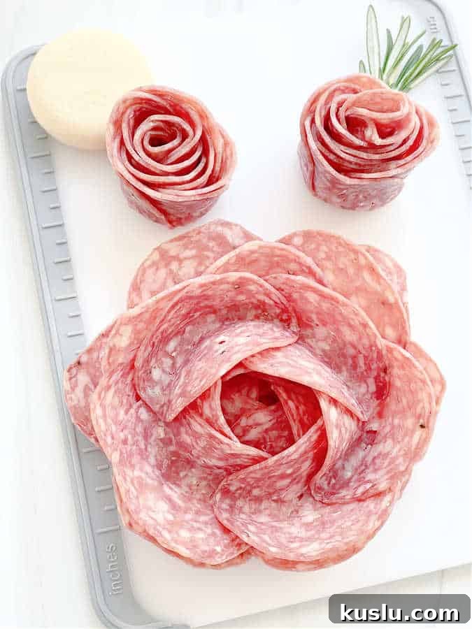 cutting board with a completed large salami rose and two smaller salami rosebuds