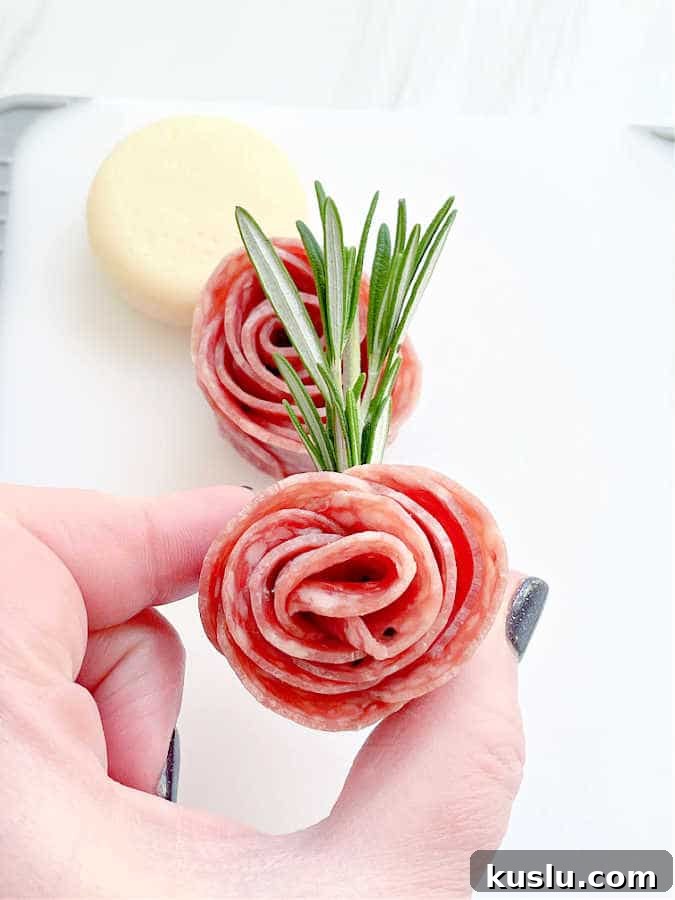 showing a salami rosebud secured with a sprig of rosemary