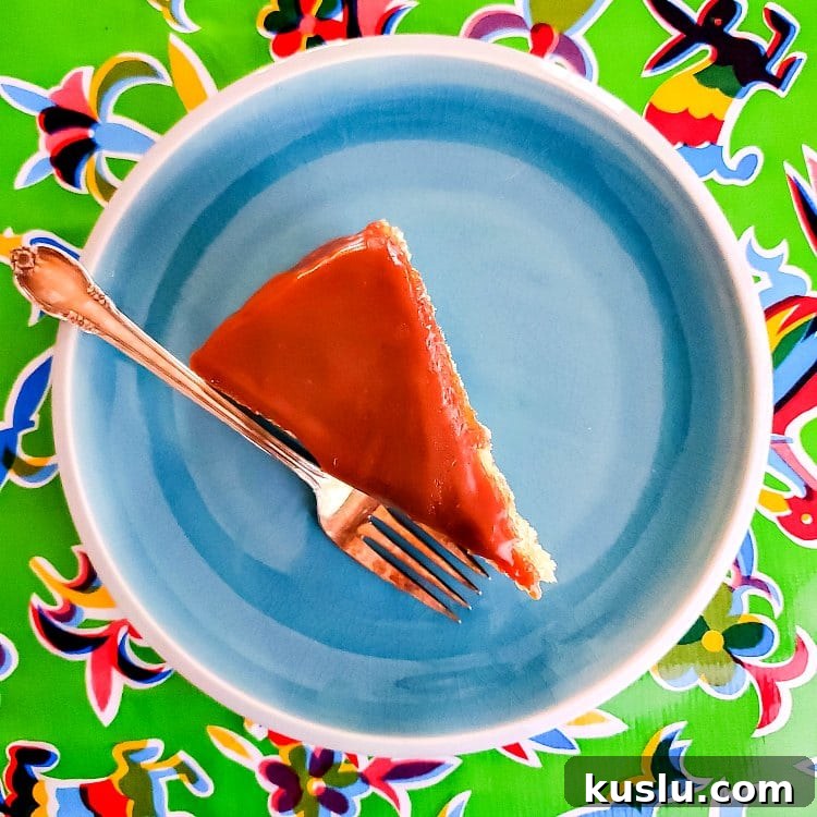 Decadent Butterscotch Cake with Silky Butterscotch Icing 3 Overhead shot of an upright slice of cake with butterscotch glaze on a blue plate with a fork.