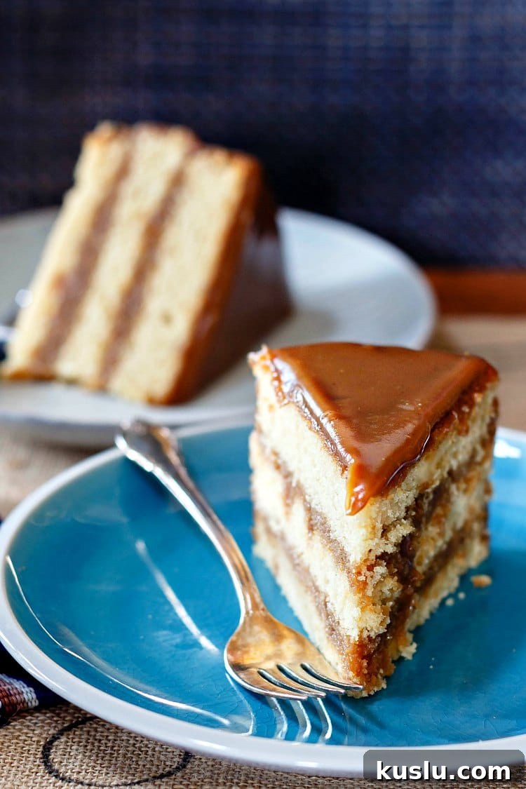 Decadent Butterscotch Cake with Silky Butterscotch Icing 4 3 layer slice of butterscotch cake upright on a blue plate with a slice of the same cake on its side in the background.