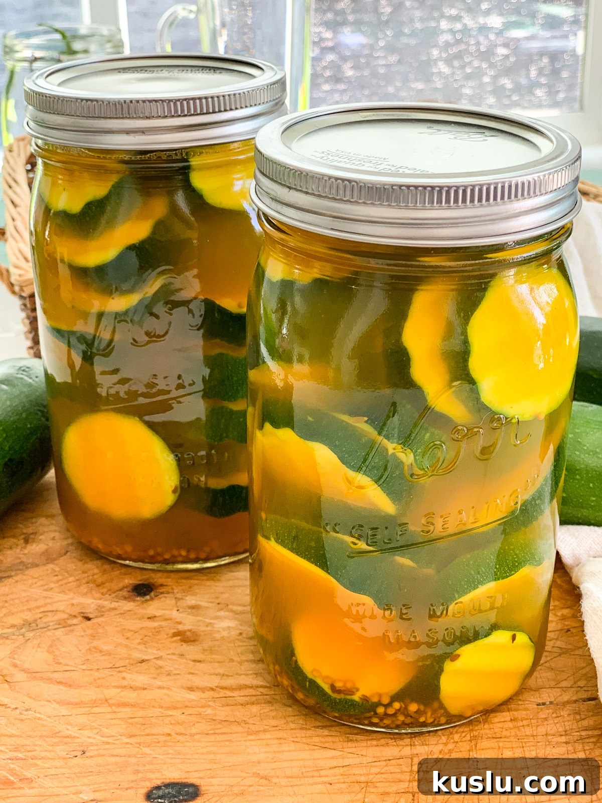 Quick Refrigerator Zucchini Pickles — No Canning Needed 13 Two mason jars filled with zucchini pickles on a cutting board