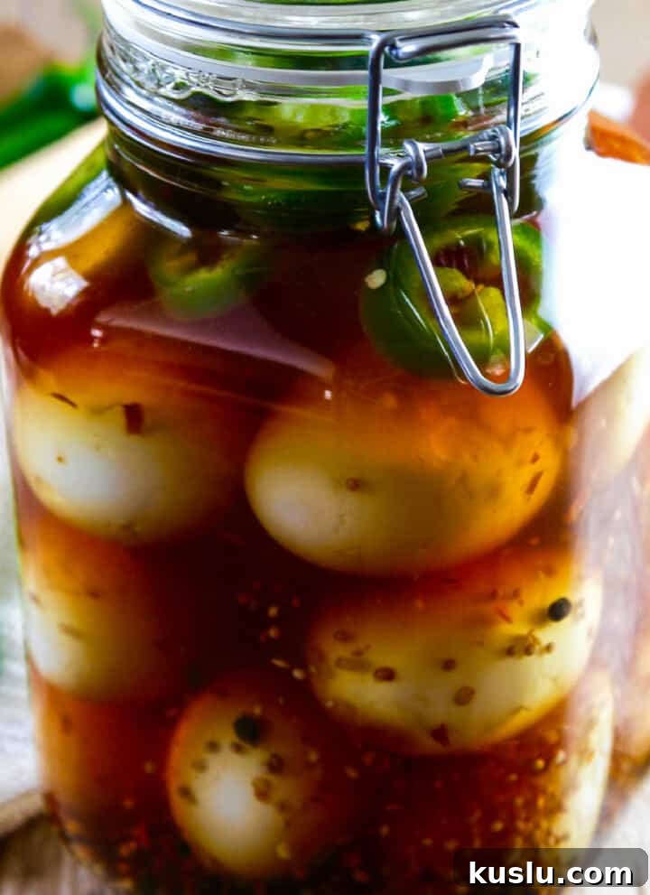 A large glass clamp jar filled with pickled eggs and jalapeno slices