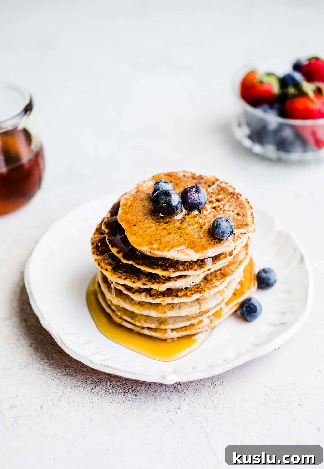 Buckwheat pancakes with syrup on a white plate.