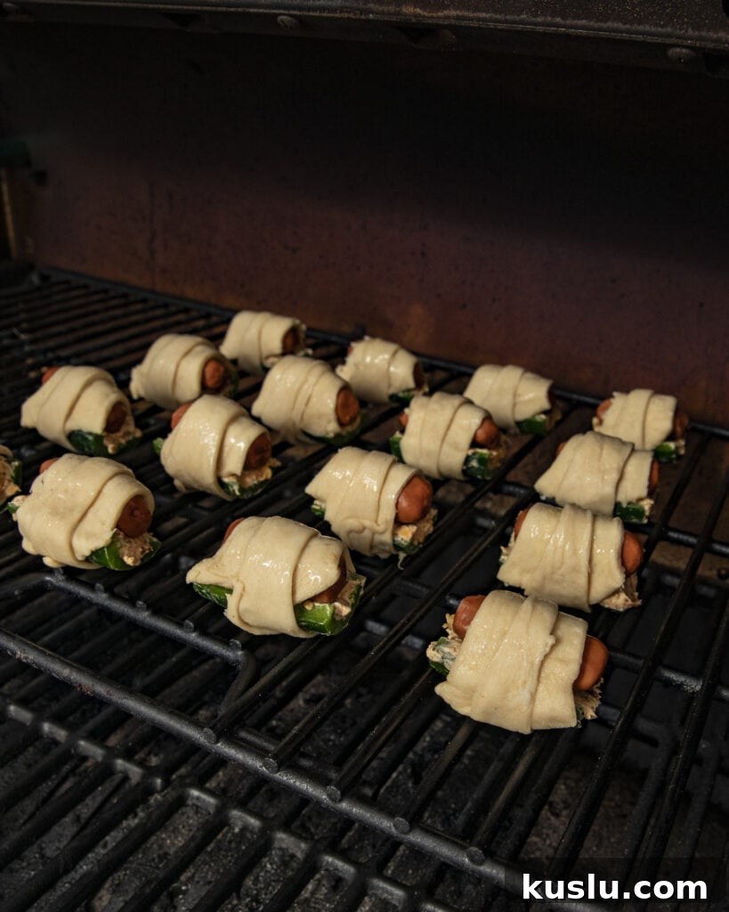 Smoked jalapeño poppers pigs in a blanket on the smoker 