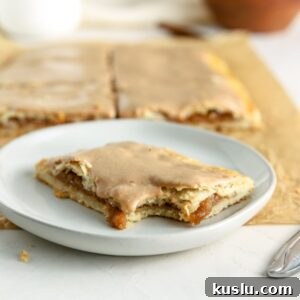 Homemade Apple Pop-Tarts Recipe for Flaky Pastry Filling 11 An apple pop tart with a bite taken out of it on a small plate.