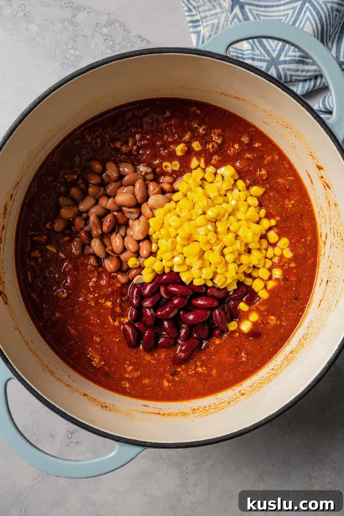 Canned corn and beans added to a pot with turkey chili.