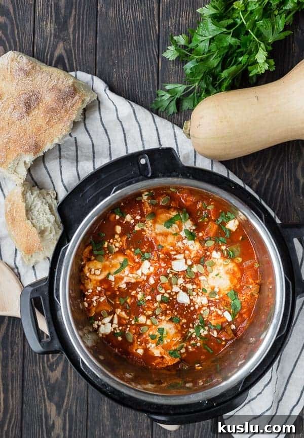 Overhead view of an Instant Pot pressure cooker filled with tomatoes, squash and eggs. Also pictured on a wooden background are a loaf of bread, a whole butternut squash, and fresh parsley.