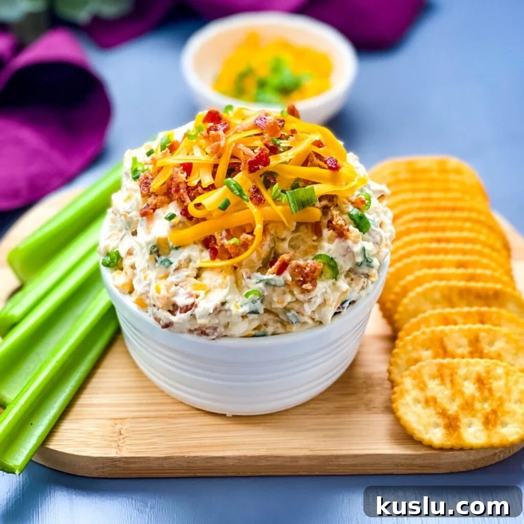 million dollar dip in a white bowl garnished with crackers and celery
