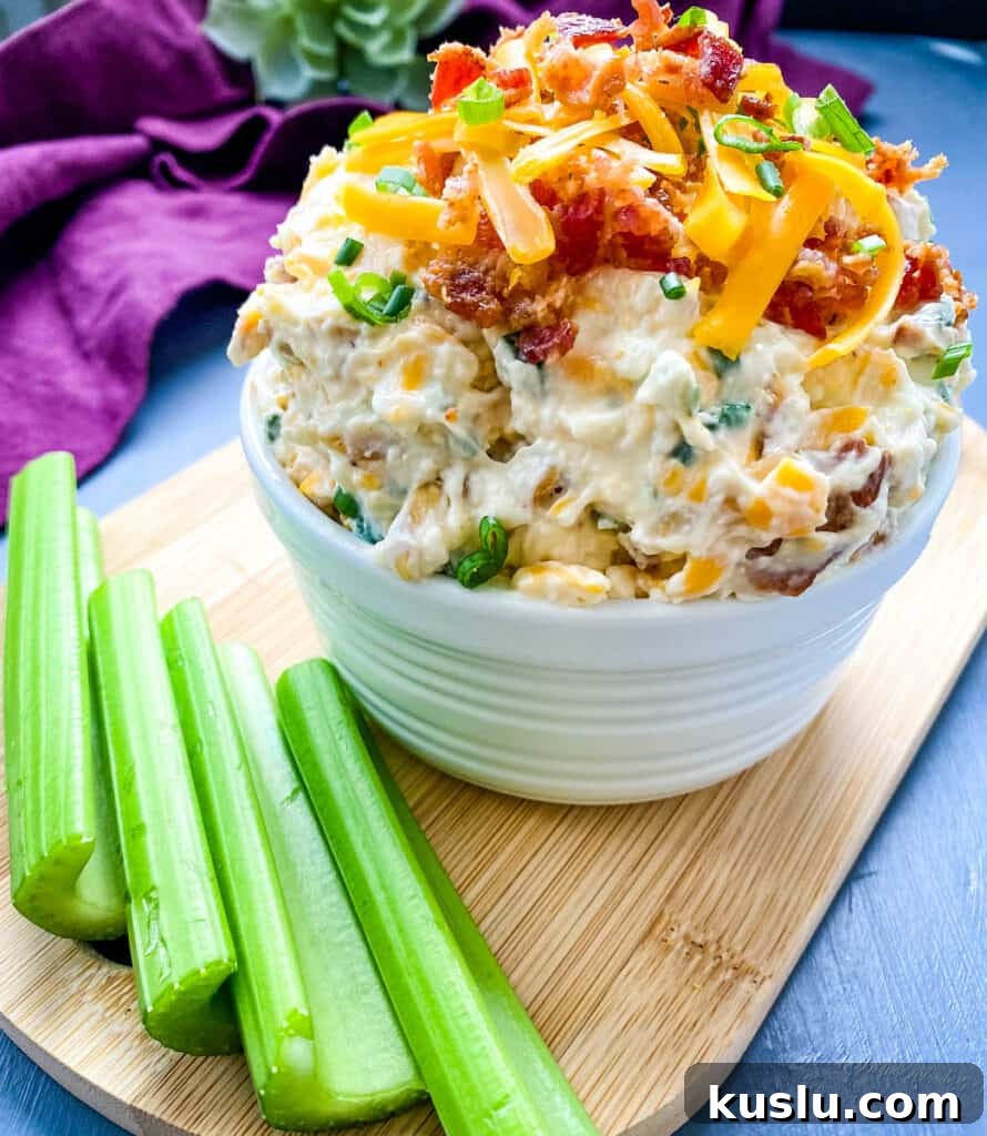 million dollar dip in a white bowl garnished with crackers and celery