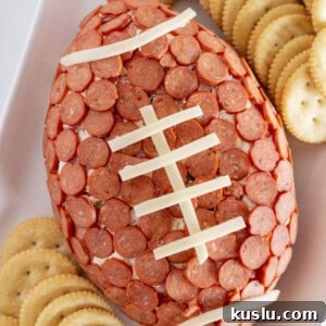 Pepperoni Pizza Football Cheese Ball Recipe: Game Day Appetizer 11 A football pepperoni cheese ball on a white tray with crackers.