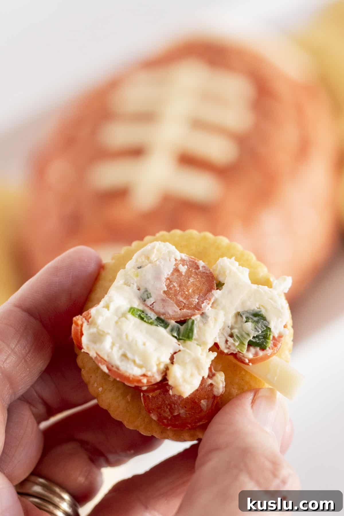 Pepperoni Pizza Football Cheese Ball Recipe: Game Day Appetizer 6 Serving the football cheese ball on a cracker.