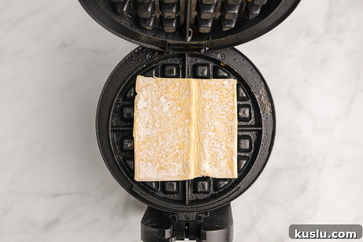 Placing puff pastry on a waffle iron.