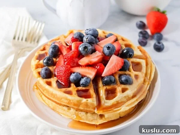 Buttermilk waffles stacked on top of each other with berries on top.