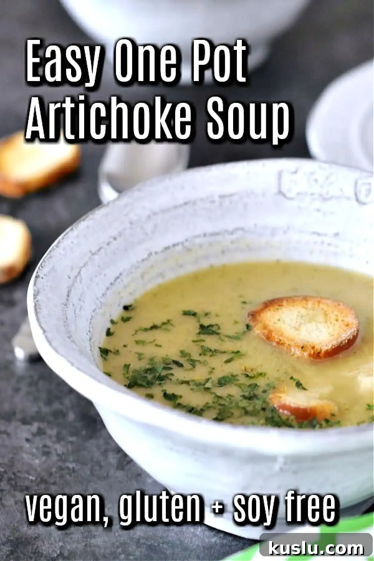Artichoke soup in bowls garnished with crisp bagel chips and chopped herbs.