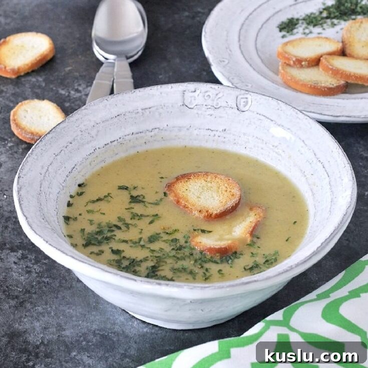 Artichoke soup in bowls garnished with crisp bagel chips and chopped herbs.