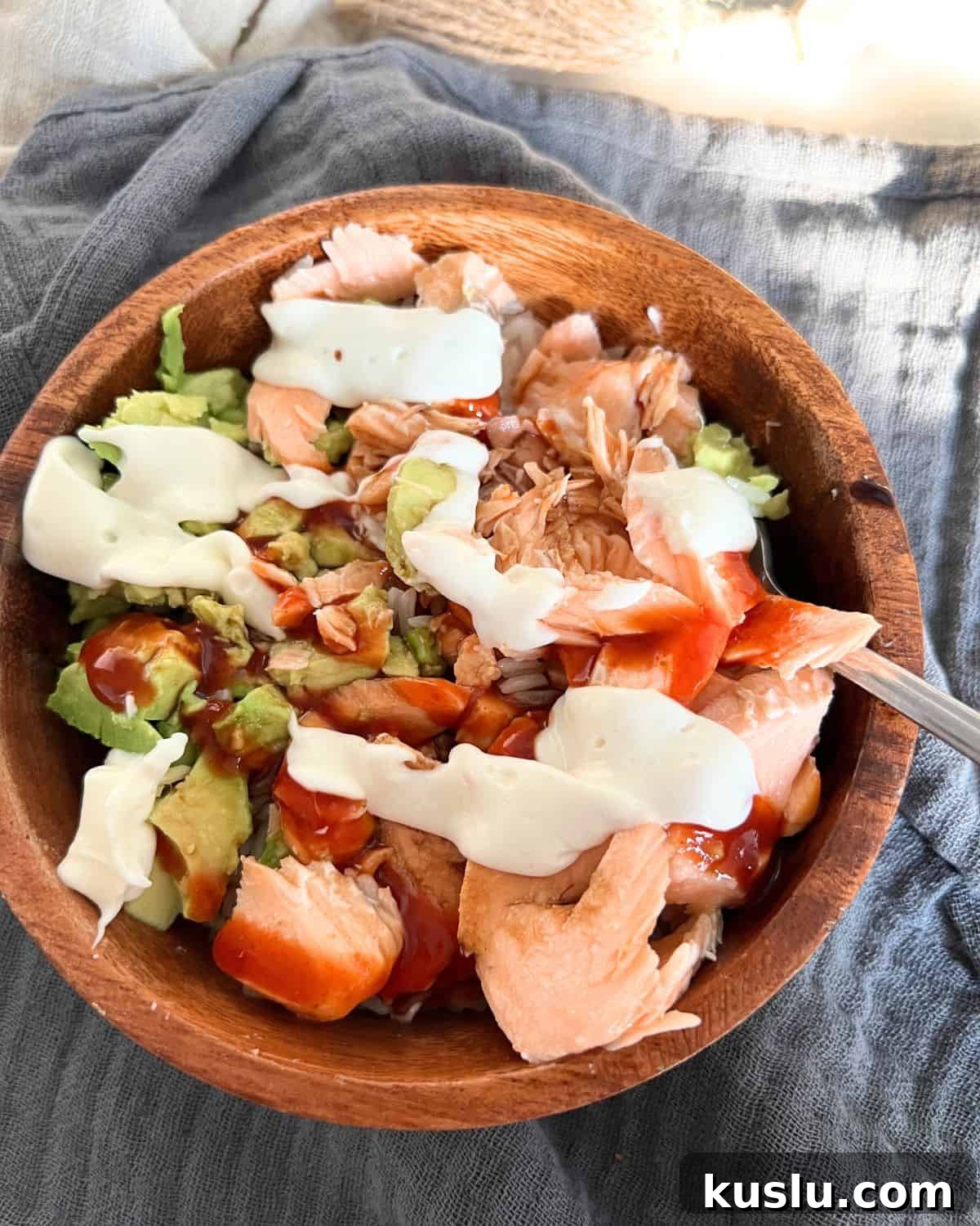 Salmon, rice, and avocado together in a wooden bowl. 
