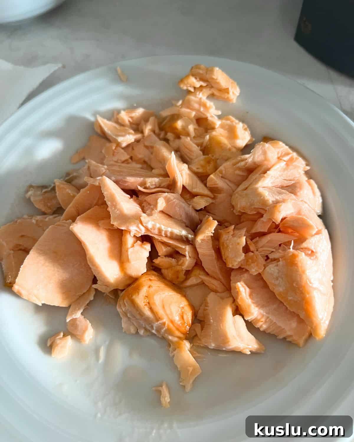 Flaked salmon on a white plate. 