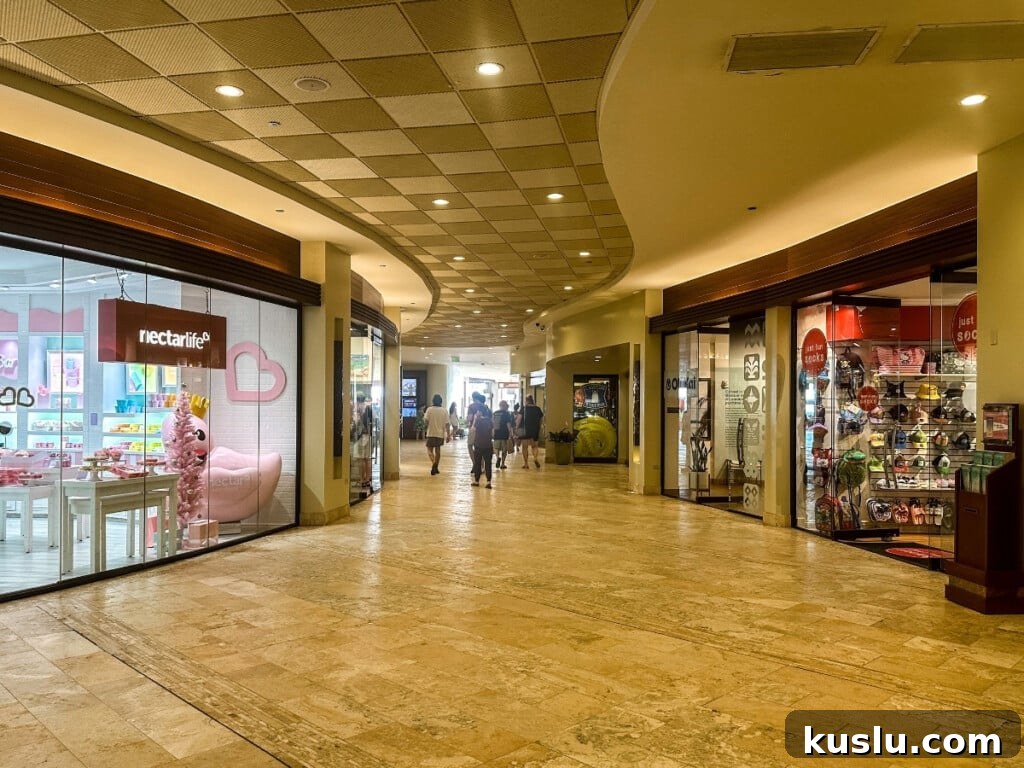 Interior view of Sheraton Waikiki shopping center featuring boutique stores, bright displays and polished walkway.