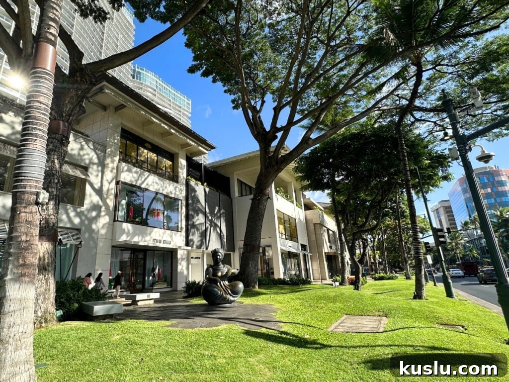 Street view of Luxury Row Shopping Center in Waikīkī featuring palm trees, designer stores & upscale retail boutiques. 