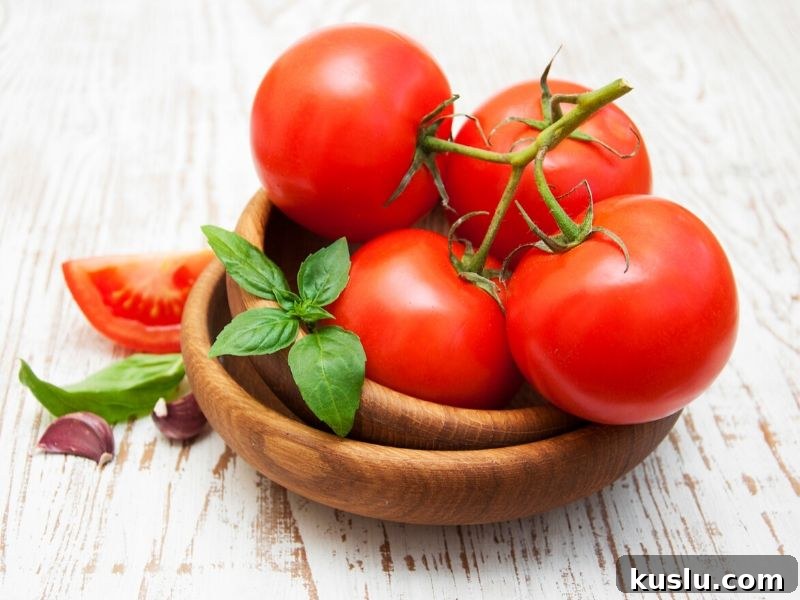 A wooden bowl filled with fresh tomatoes on a counter.