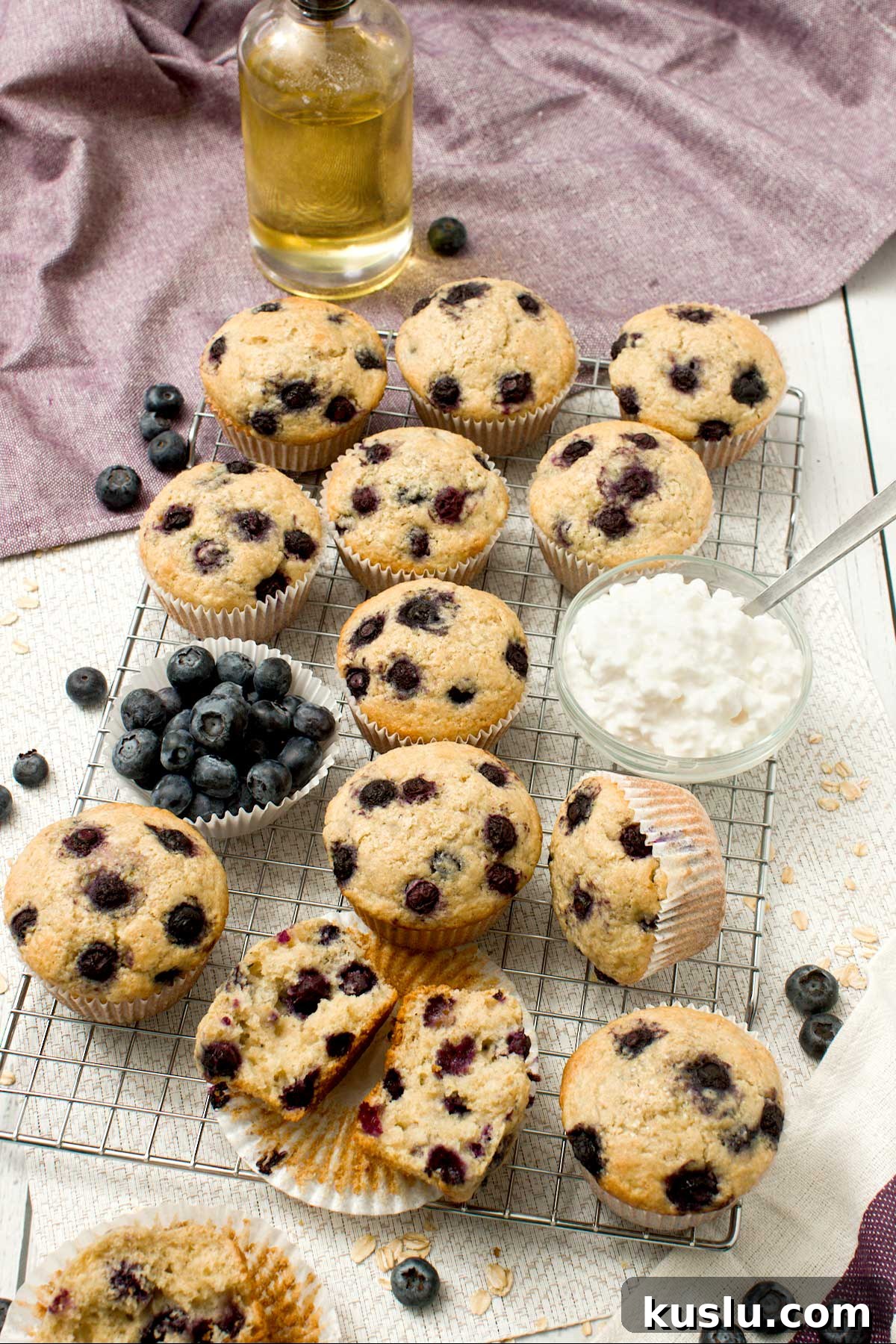 A dozen blueberry cottage cheese muffins on a cooling rack.