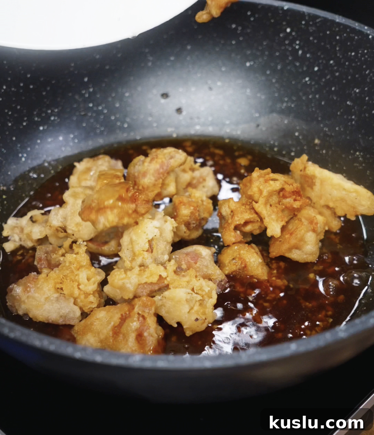 Crispy Korean Fried Chicken Recipe: How to Make Dakgangjeong 9 Double-fried chicken is added to the glossy soy garlic honey glaze in a pan, ready to be tossed and coated.