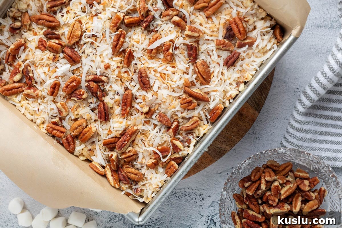 Coconut Pecan Rice Krispie Treats Recipe for Crispy Sweets 11 overhead of coconut pecan rice krispie treats in a parchment lined pan next to a bowl of pecans