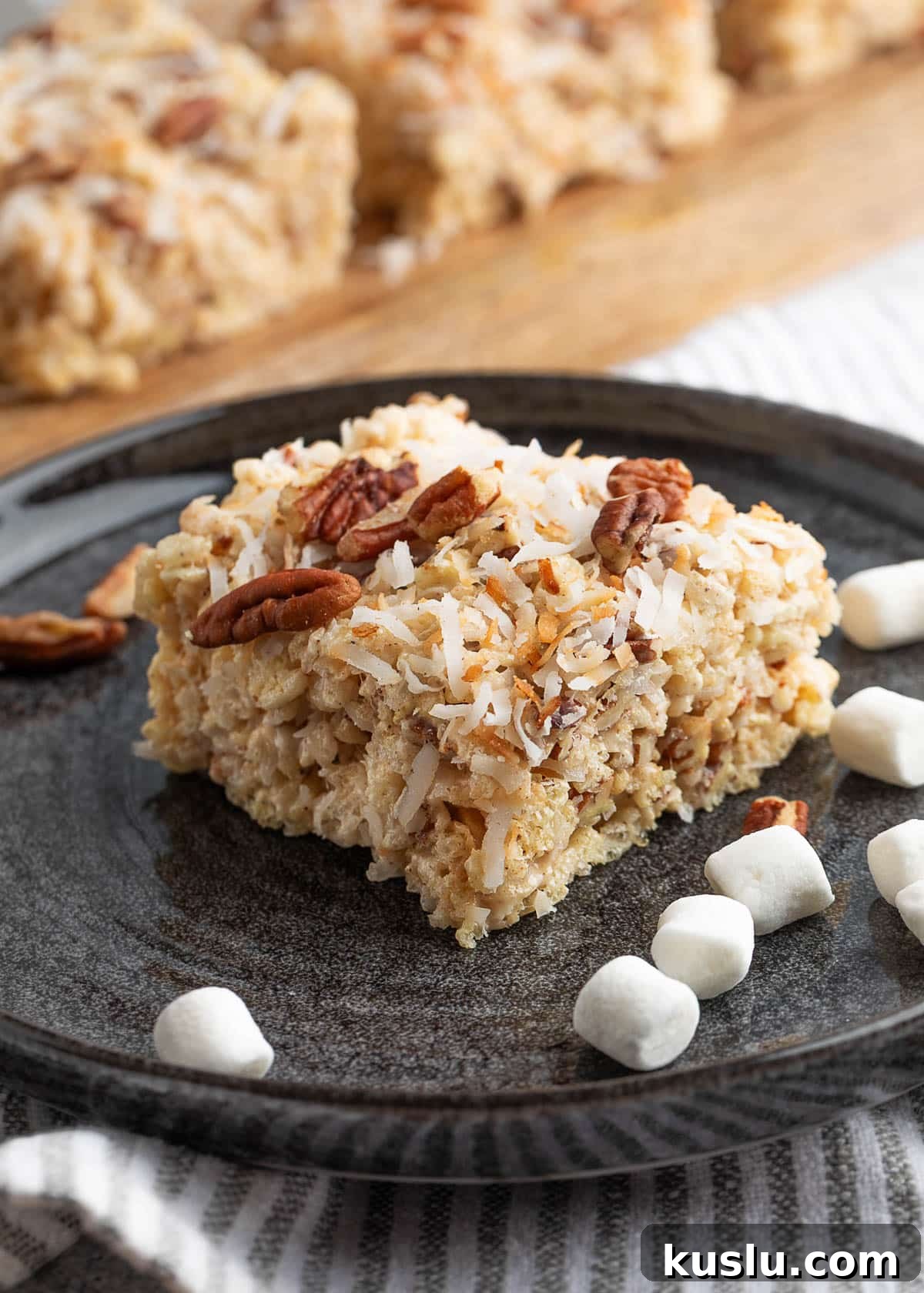 Coconut Pecan Rice Krispie Treats Recipe for Crispy Sweets 13 coconut pecan rice krispie treat served on a black plate scattered with mini marshmallows