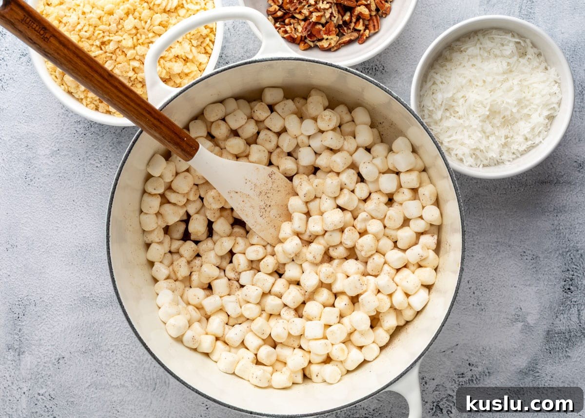 Coconut Pecan Rice Krispie Treats Recipe for Crispy Sweets 7 mini marshmallows added to a pot of brown butter with a wood handled spatula
