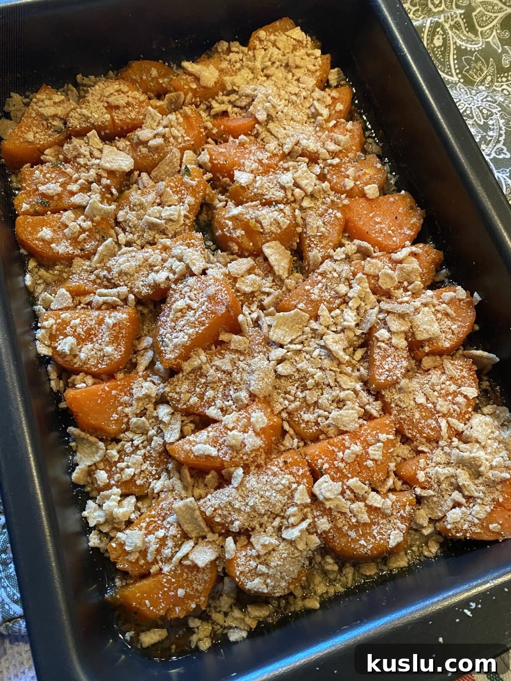 Slices of sweet potato laid out in a baking pan topped with crushed Cinnamon Toast Crunch.
