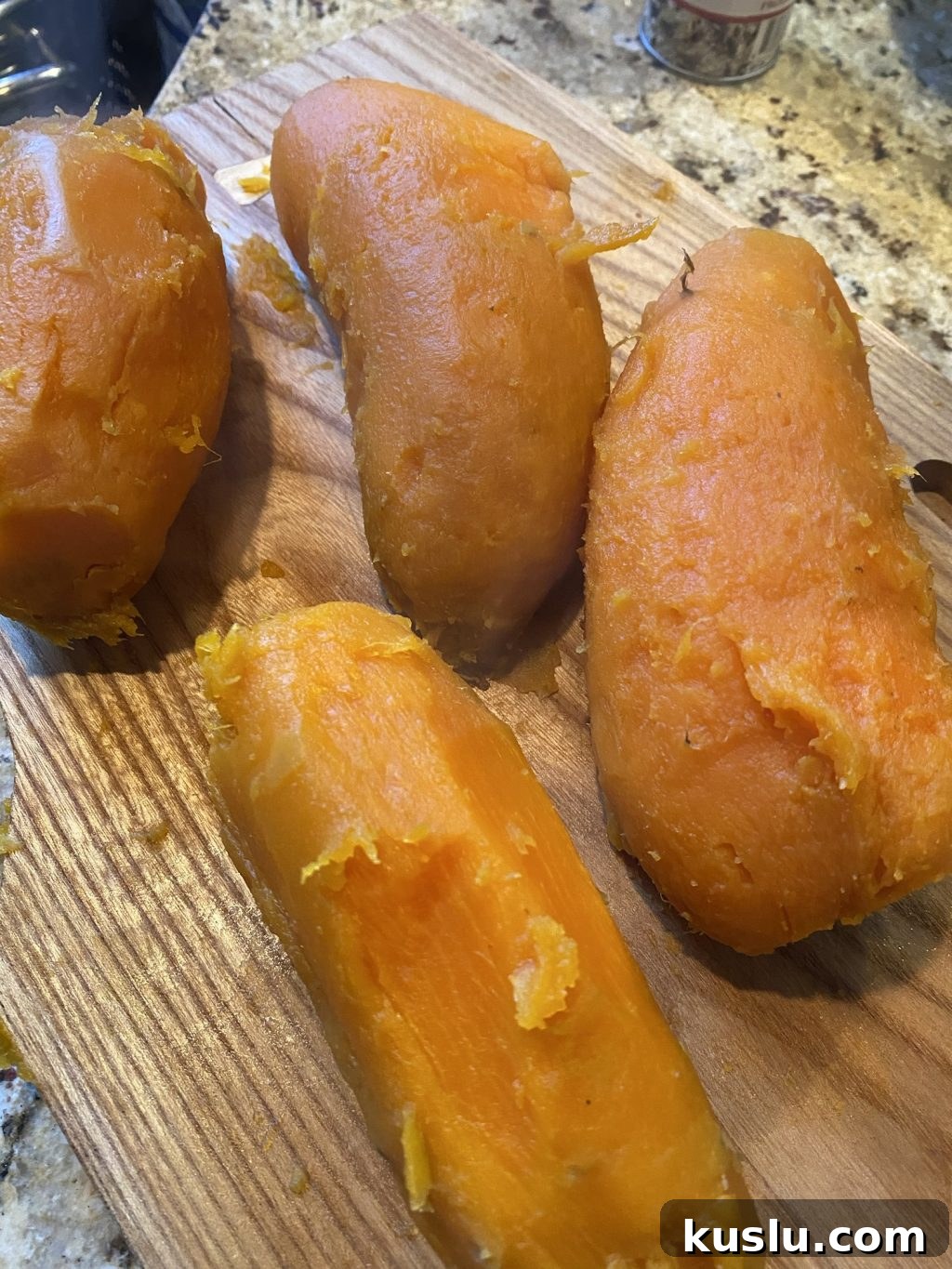 Peeled, cooked sweet potatoes on a wooden cutting board.