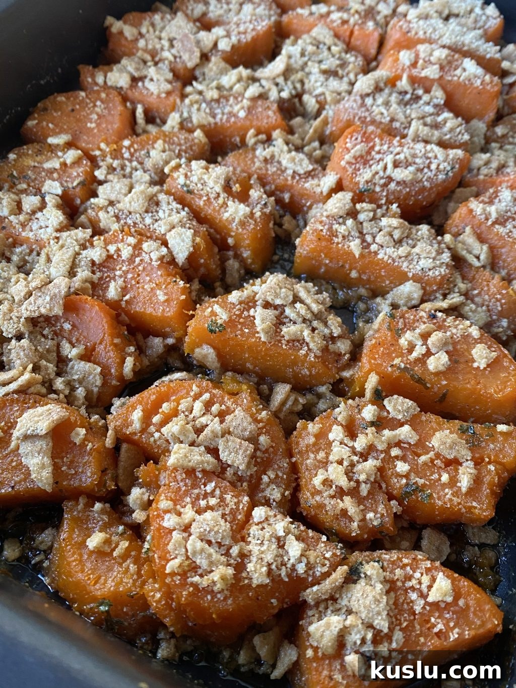 A close up shot of the sliced, cooked sweet potatoes topped with crushed cinnamon toast crunch.