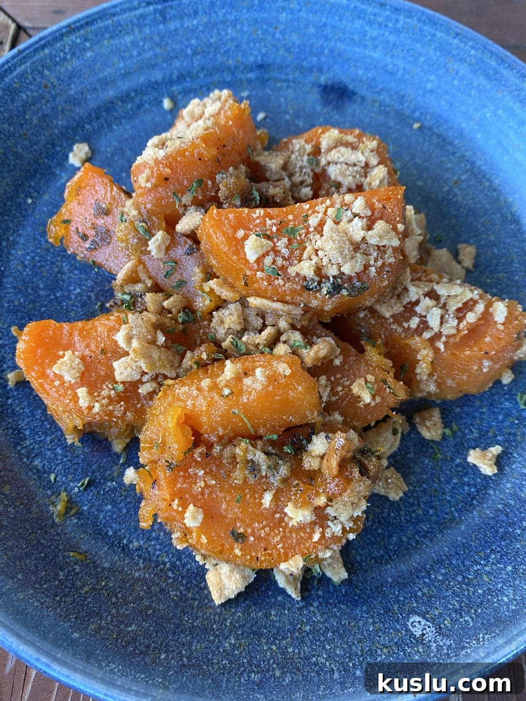 Baked sweet potato slices with crunchy cereal topping on a blue plate.
