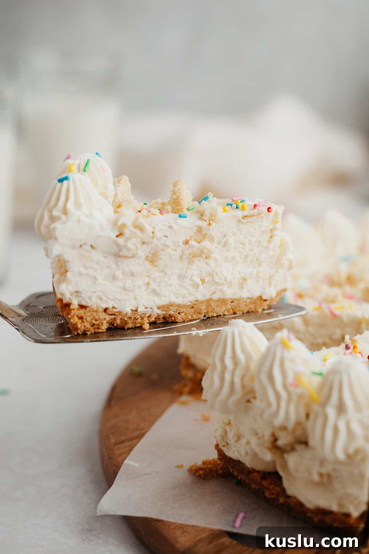 A slice of no bake cheesecake covered in rainbow sprinkles being lifted out of the cheesecake
