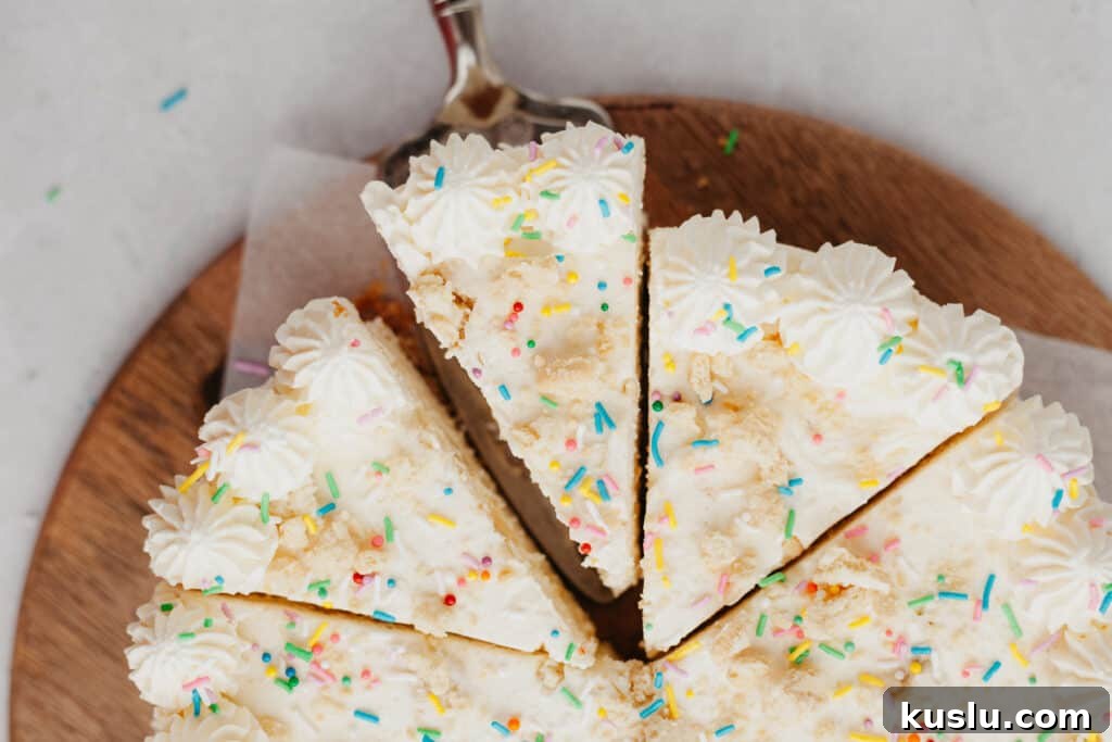 Overhead shot of a cheesecake covered in rainbow sprinkles. Three slices have been cut