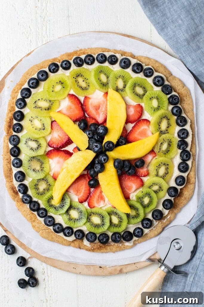 Fresh Fruit Pizza on a Crisp Cookie Crust: Summer Dessert Recipe 9 A fruit pizza shown with a pizza cutter.
