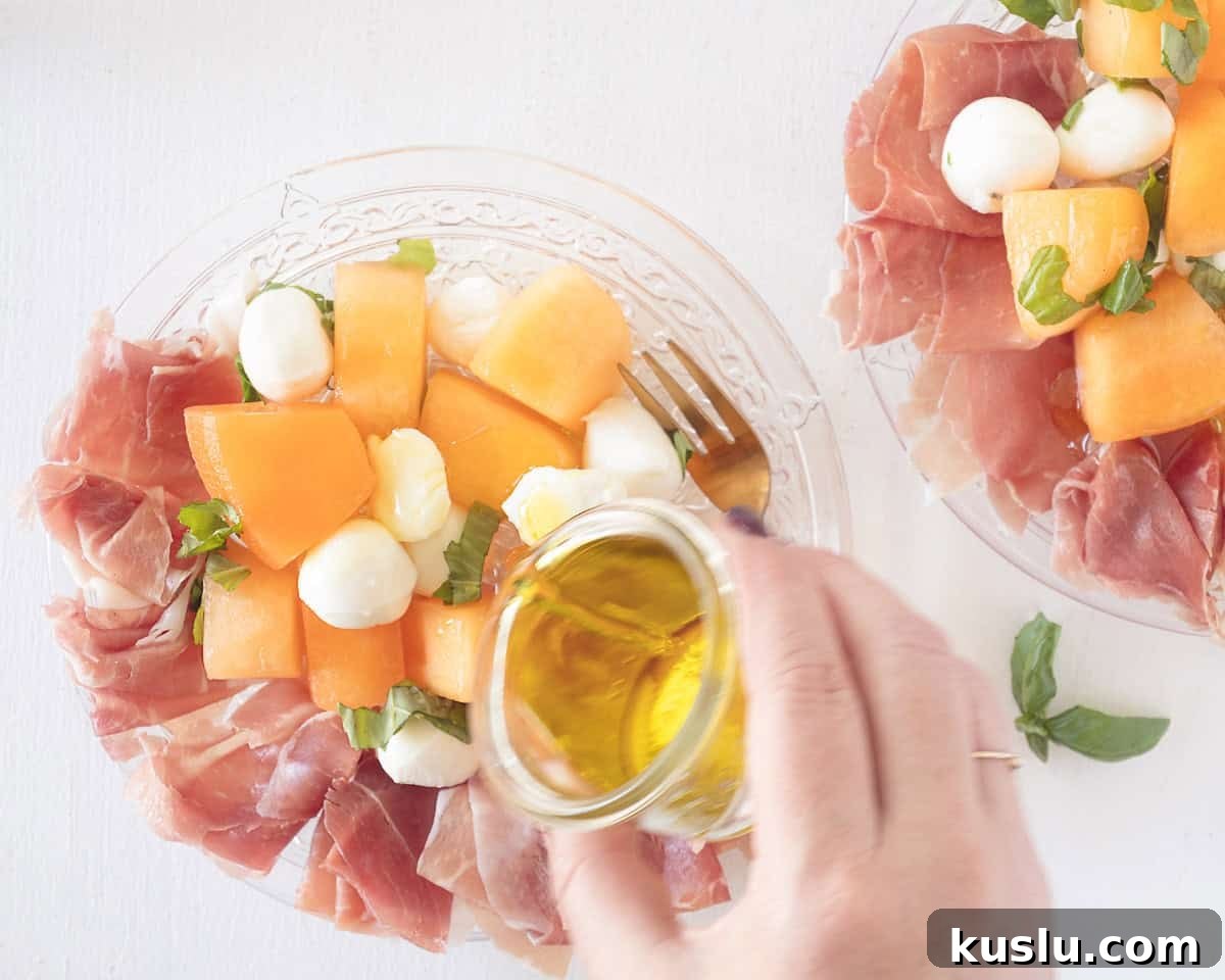 Olive oil is poured on top of the melon, mozzarella and parma ham salad